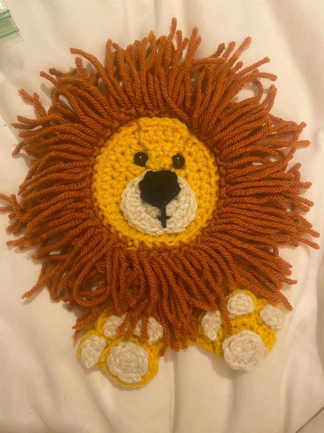 Lion Mane Wall Piece: A lion face with a thick, hand-looped yarn mane in rust and gold.