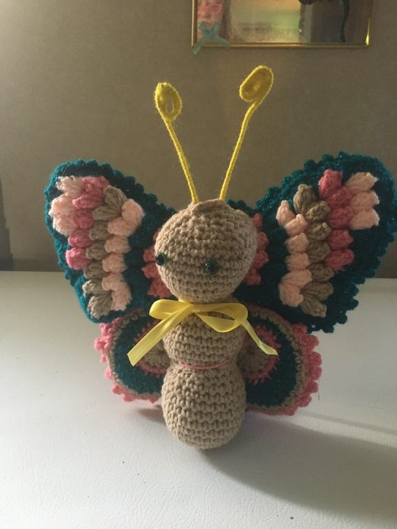 Butterfly Amigurumi: A stuffed butterfly with a ribbon bow and wings in teal, rose and tan.