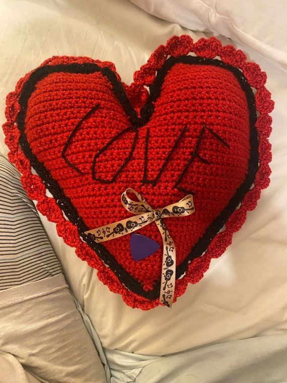 Love Heart Pillow: A red heart pillow stitched with LOVE, trimmed in black with a ruffled edge.