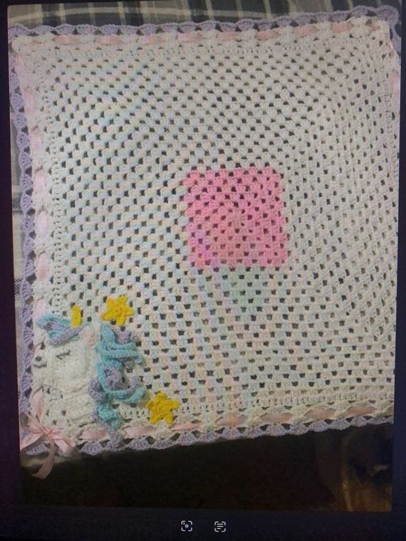 Unicorn Baby Blanket: A soft white lace-stitch baby blanket with a pink center and a unicorn in the corner.
